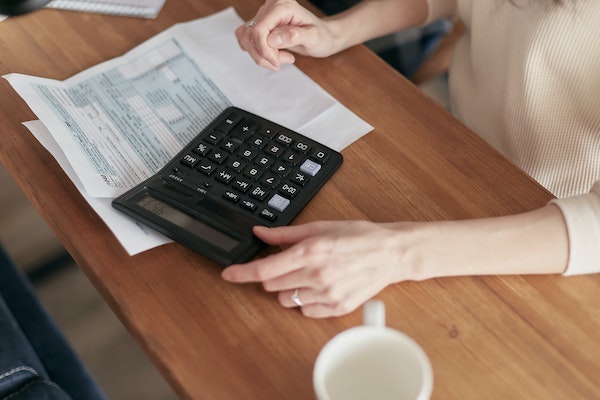 Pessoa à mesa de escritório, usando calculadora e com um documento ao lado, simbolizando o cálculo da aposentadoria por idade urbana