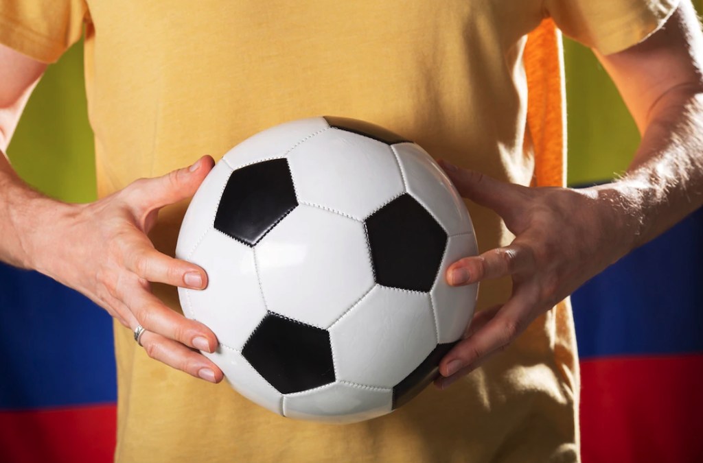 Bola de futebol sendo segurada por uma pessoa, simbolizando aposentadoria no esporte
