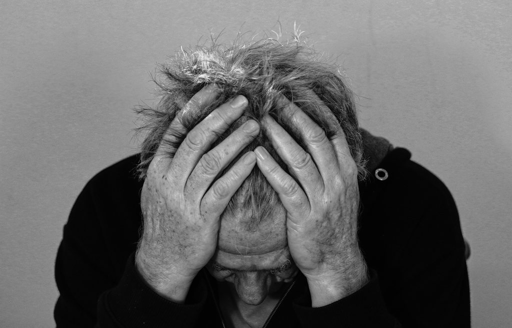 Homem idoso com mãos na cabeça, simbolizando esquizofrenia e aposentadoria por invalidez