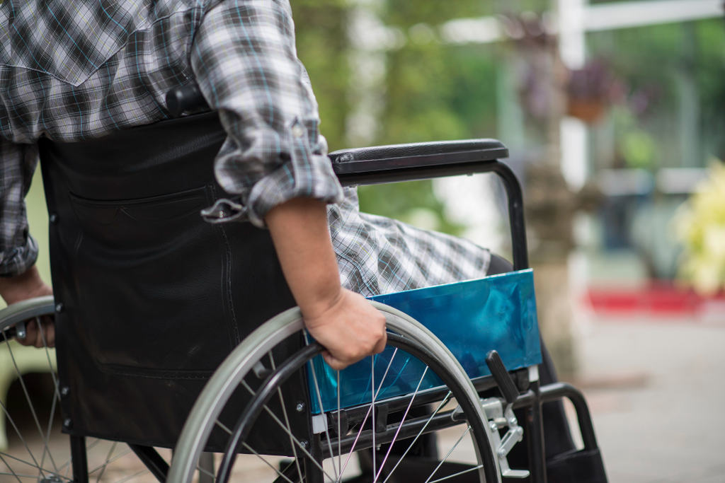 Homem em cadeira de rodas. Uma pessoa com paralisia é um exemplo de pessoas que têm direito ao BPC LOAS