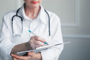 Médica com papel e prancheta nas mãos, possivelmente fazendo um laudo de perícia resolutiva